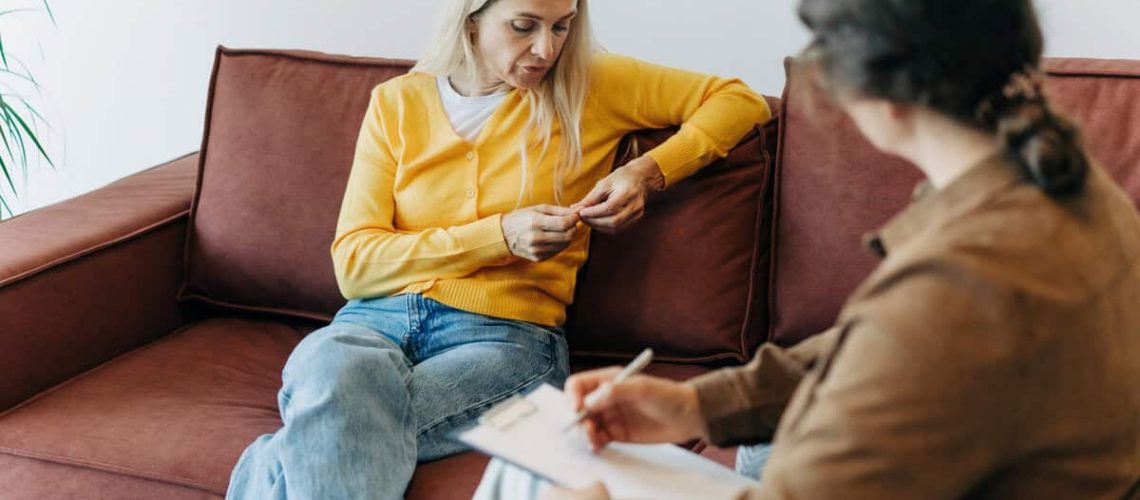 A woman patient, sitting on the couch during a consultation with a psychologist, talks about her difficulties in life, stress and relationship problems.