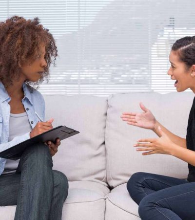 Upset woman speaking to her therapist while she is taking notes