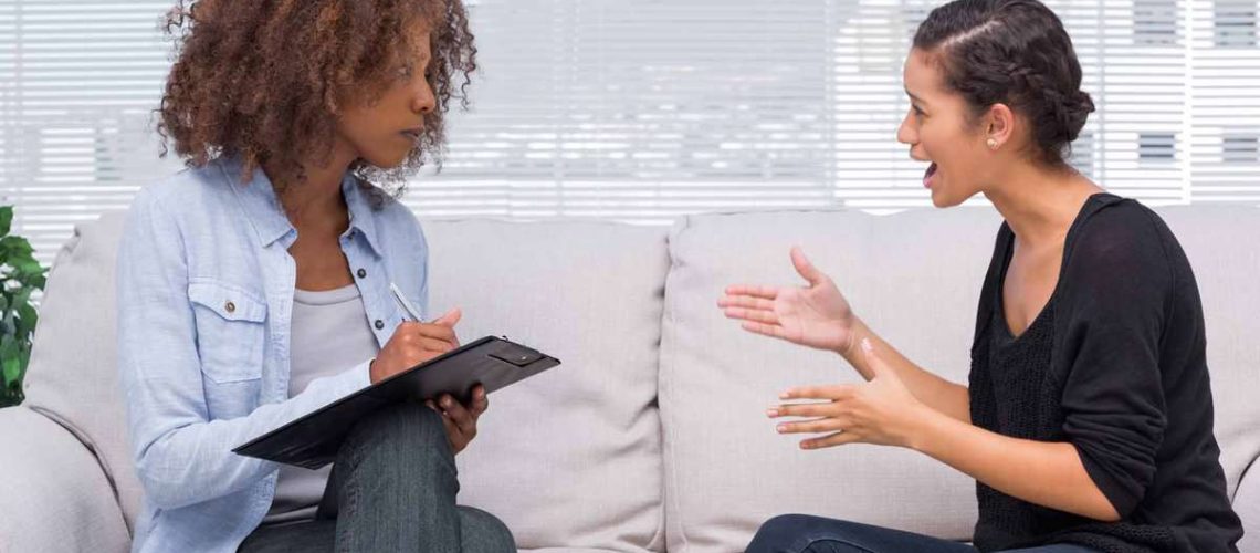 Upset woman speaking to her therapist while she is taking notes