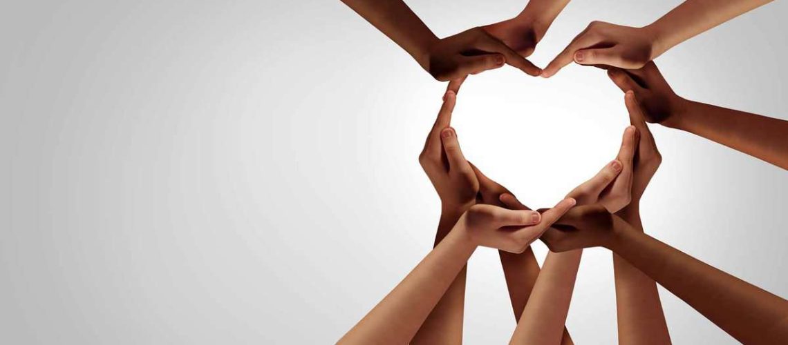 Unity and diversity partnership as heart hands in a group of diverse people connected together shaped as a support symbol expressing the feeling of teamwork and togetherness.