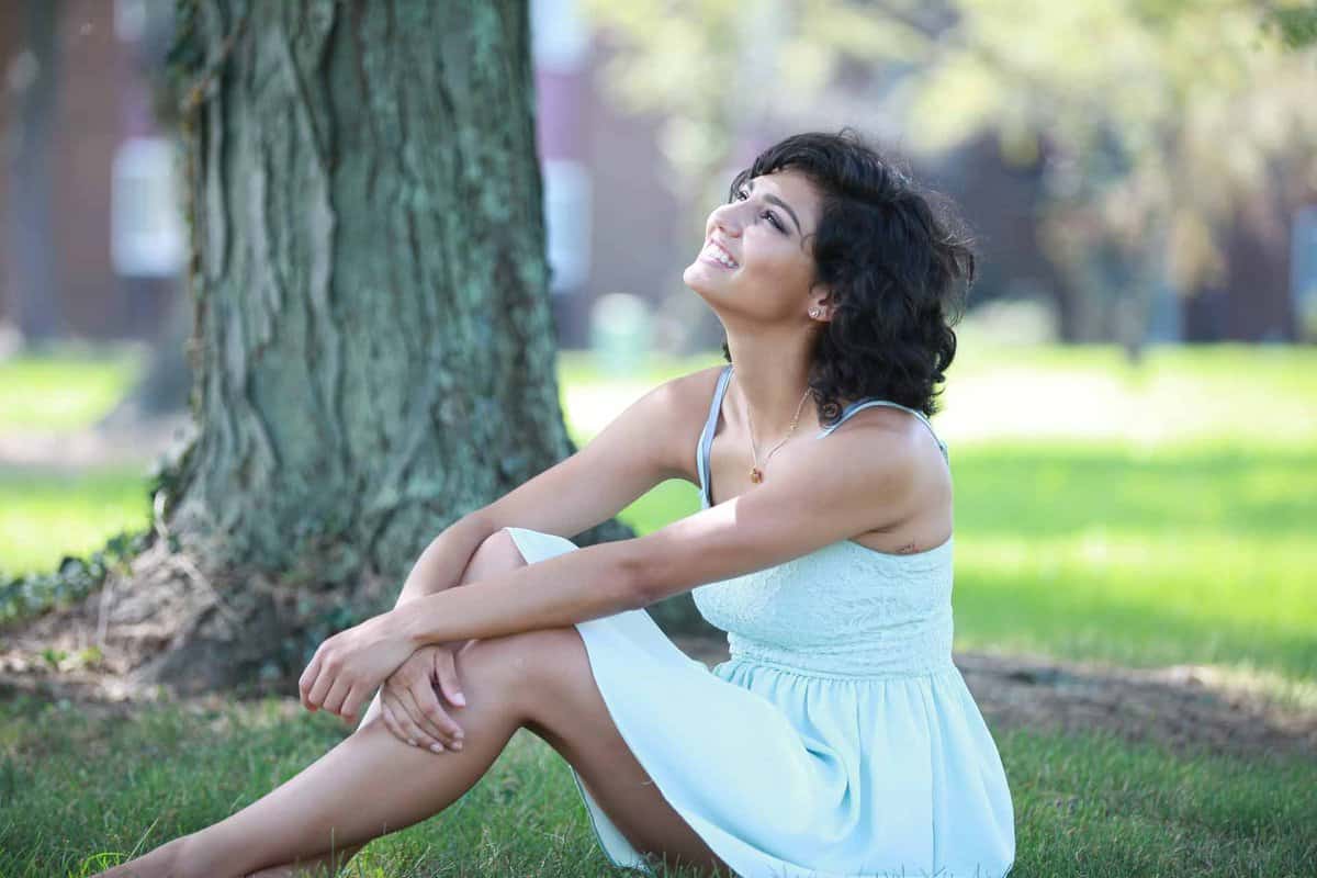 Beautiful hispanic girl sitting on the grass looking to the sky